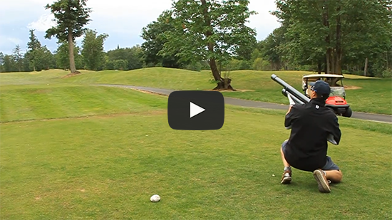 Man sitting with golf ball launcher ready to fire