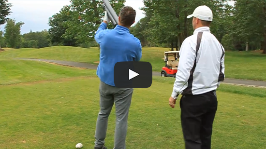 Two men standing with golf ball launcher ready to fire